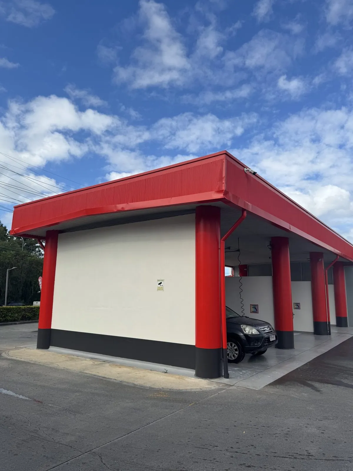 Freshly repainted car wash with red canopy and white walls on the Gold Coast