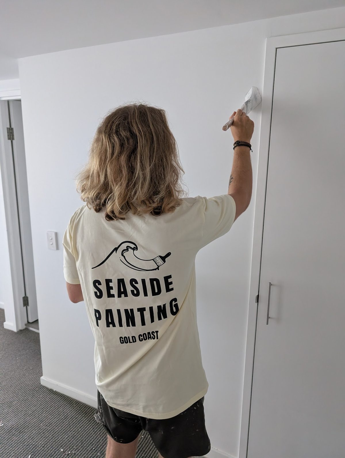Seaside Painting crew member in a branded tee painting a door on the Gold Coast