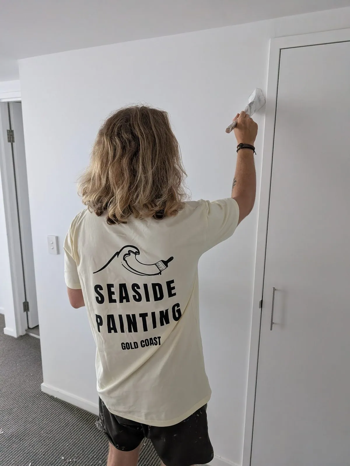 Seaside Painting crew member in a branded tee painting a door on the Gold Coast